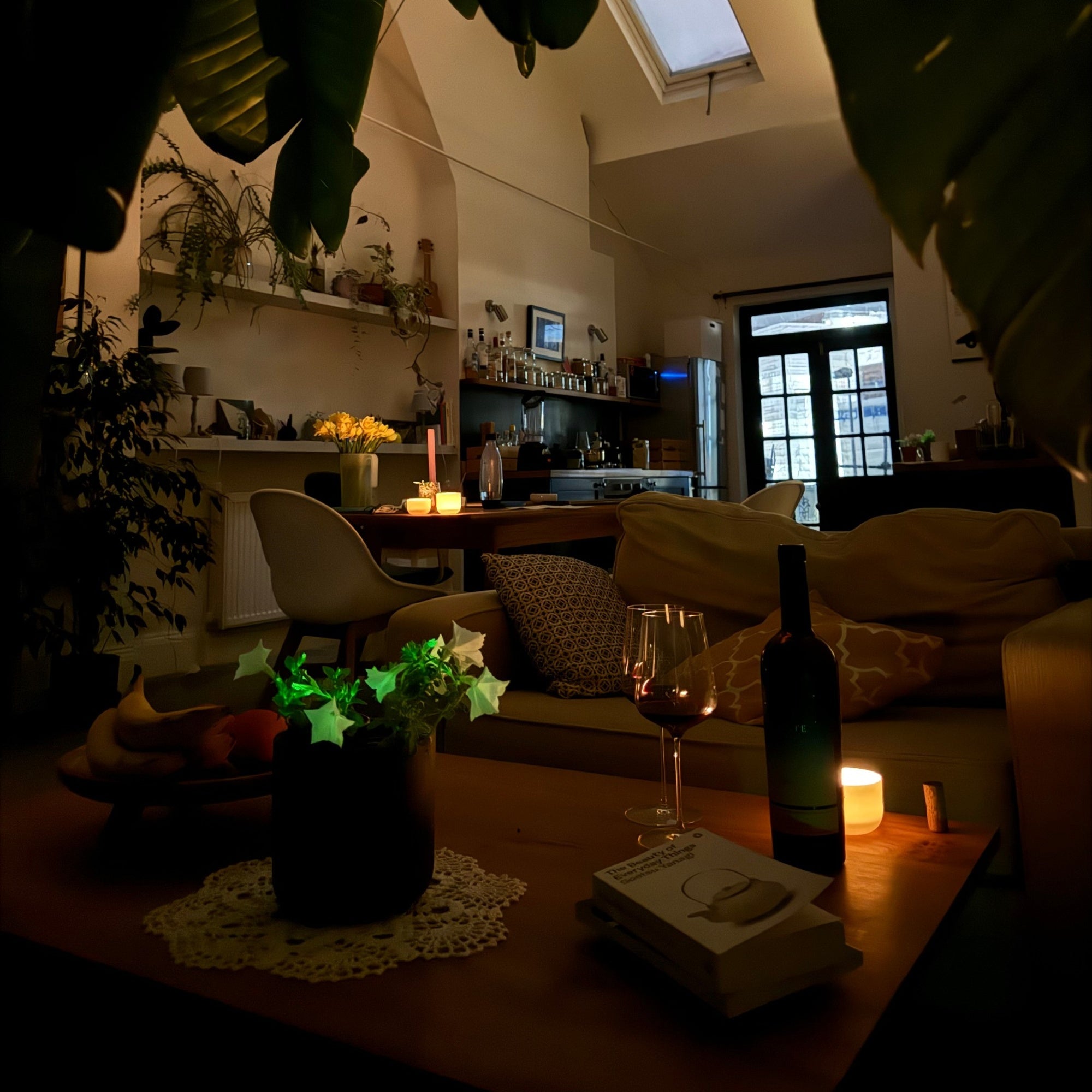 Firefly Petunia bioluminescent plant glowing on a table in a cozy living room at night